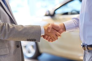 auto business, car sale, deal, gesture and people concept - close up of male handshake in auto show or salon